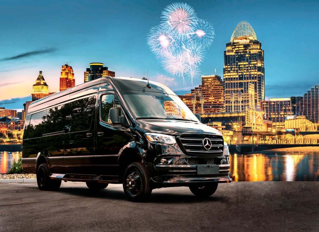 Exterior photo of Elite Transportation limo van in front of the Cincinnati skyline which is illuminated by fireworks