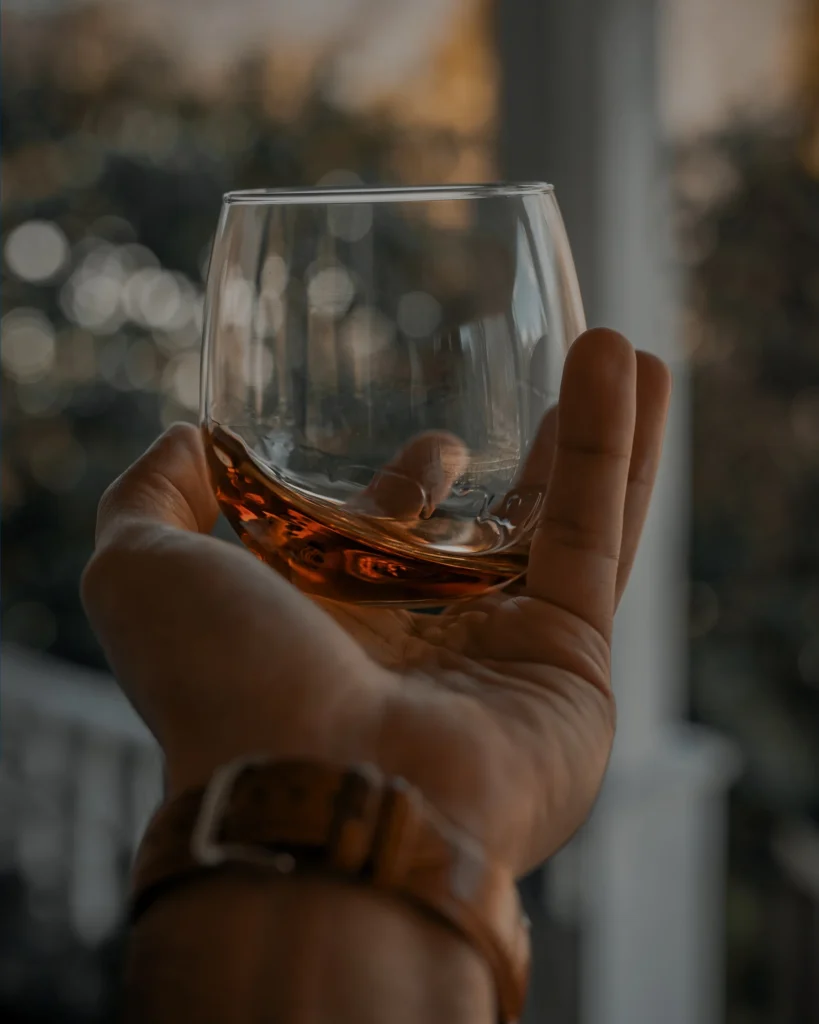 whiskey glass with bourbon in hand