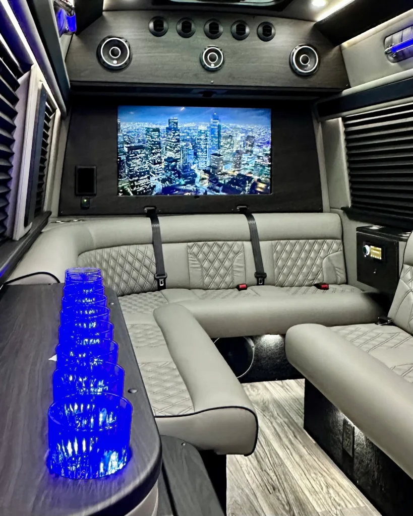 interior view of limo bus focused on the bar, back bench seat, and flat screen tv